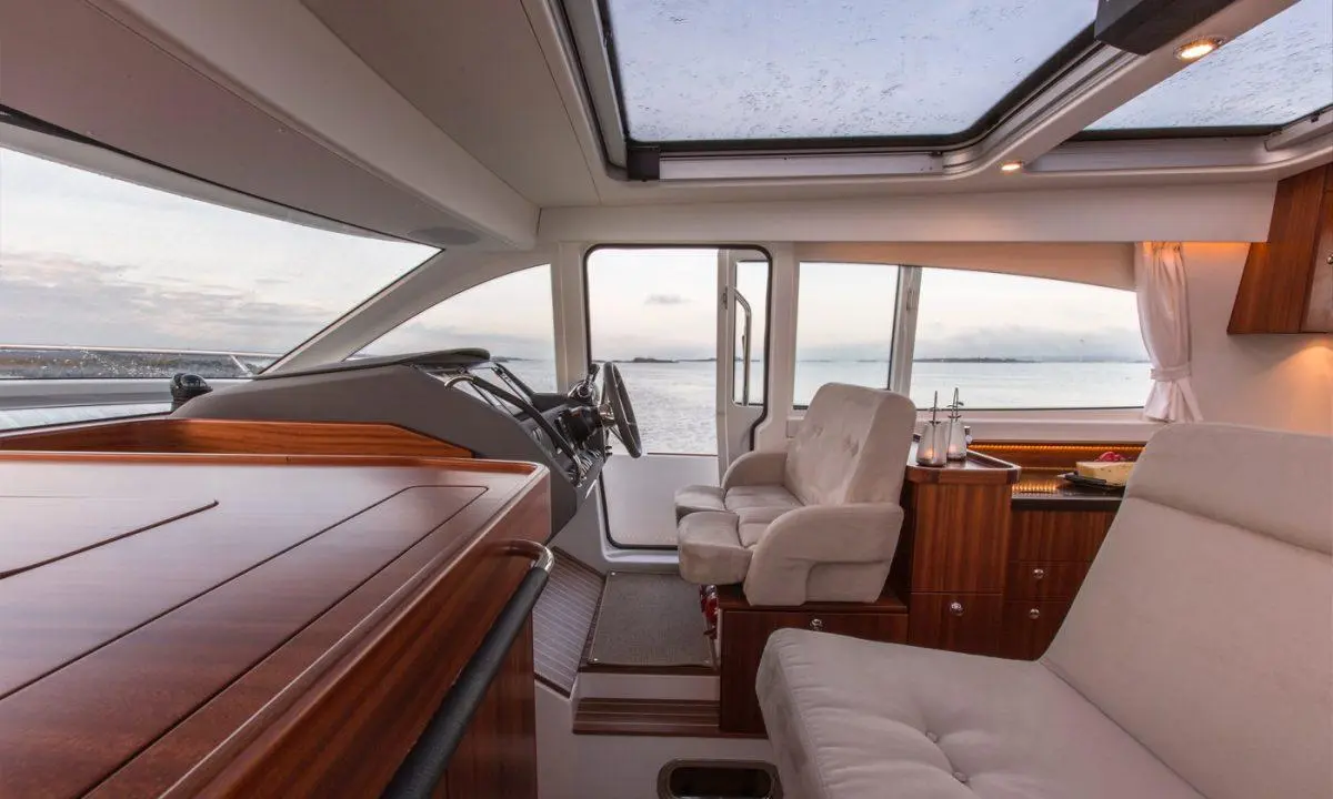 A luxurious yacht interior featuring a helm station and comfortable seating, with panoramic views of the tranquil sea.